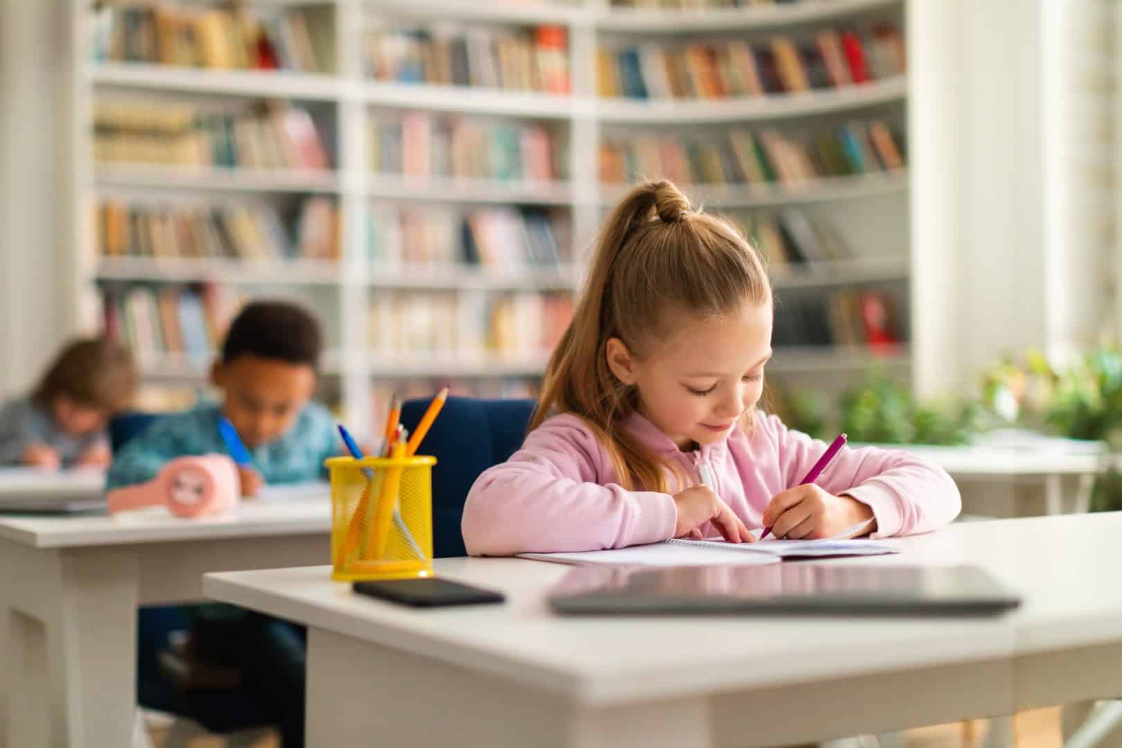 A kid writing on a paper in the library